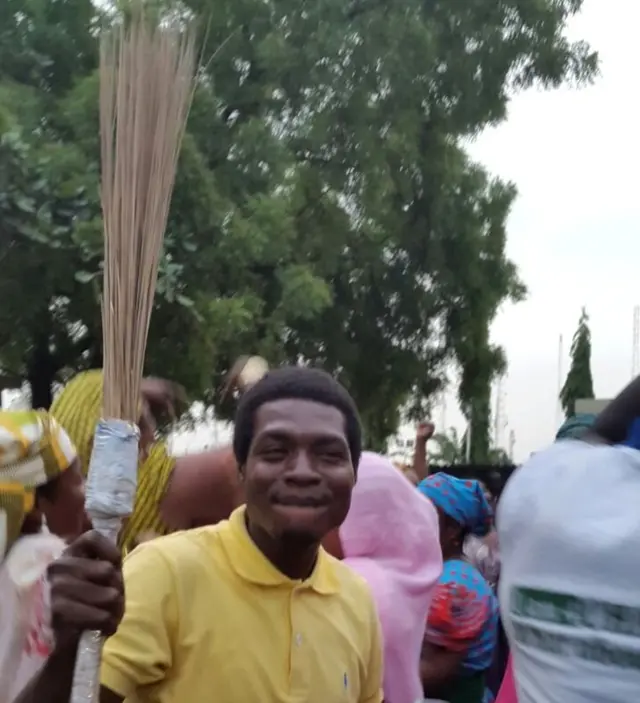 An APC supporter holding a broom