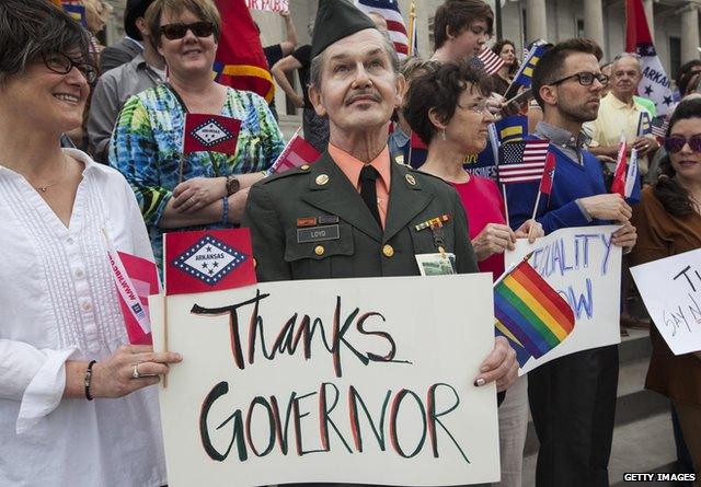 Man in military uniform with sign that reads "Thanks Governor"