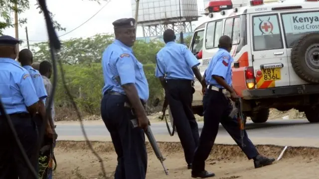 Police officers take positions outside the Garissa University College as an ambulance carrying the injured going to a hospital, during an attack by gunmen in Garissa, Kenya