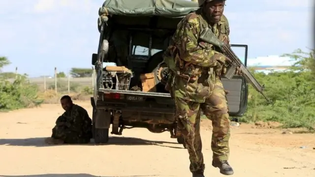 Kenyan soldiers run for cover near the perimeter wall where attackers are holding up at a campus in Garissa 2 April 2015