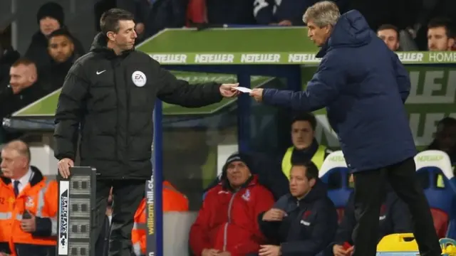 Manuel Pellegrini hands fourth official Lee Probert a peice of paper