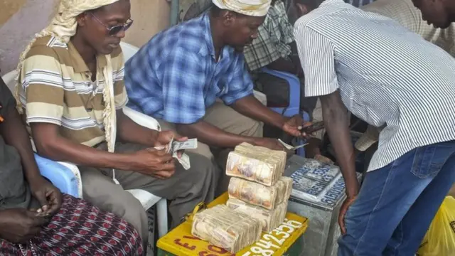 A customer of Dahabshiil, Somalia's largest remittance company, exchanges his US dollar bills for Somali shillings outside the company's headquarters in Mogadishu, Somalia on 16 February 2014