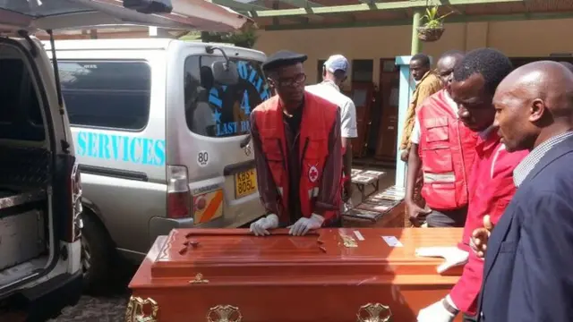 relatives look on as coffins carrying a victim's body are loaded into a vehicle