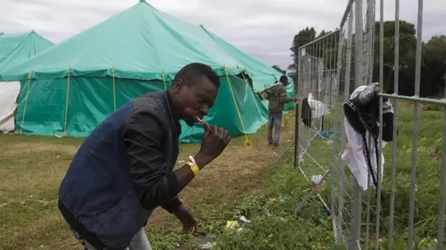 A foreign man brushes his teeth in a camp on a sports field in Isipingo, south of Durban