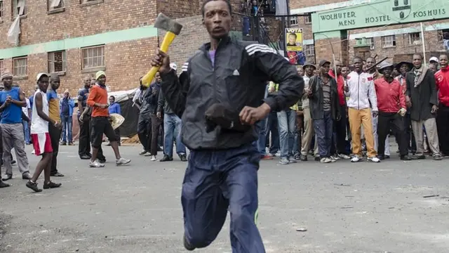 A man armed with an axe threatens members of the press in Johannesburg