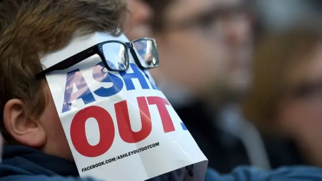 Newcastle United fan covers his face with a protest sign