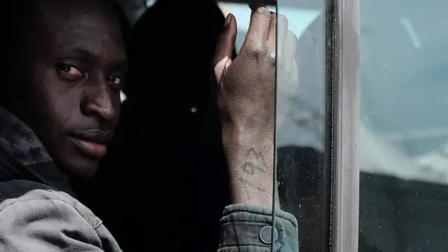 A rescued migrant with a number on his right arm, sits on bus after disembark off the Italian Guardia di Finanza vessel Denaro at the Sicilian harbour of Catania on April 23, 2015.