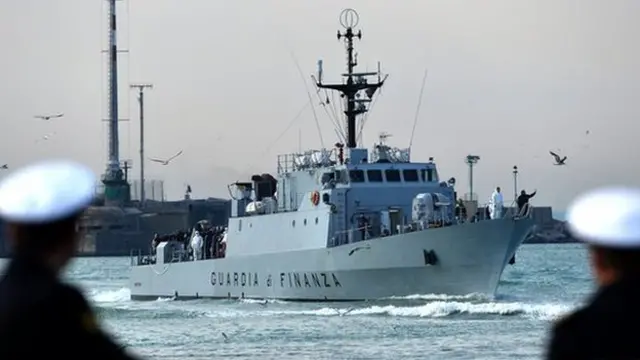 Rescued migrants stand aboard the Italian Guardia di Finanza vessel Denaro upon arrival to the Sicilian harbour of Catania on 23 April 2015.