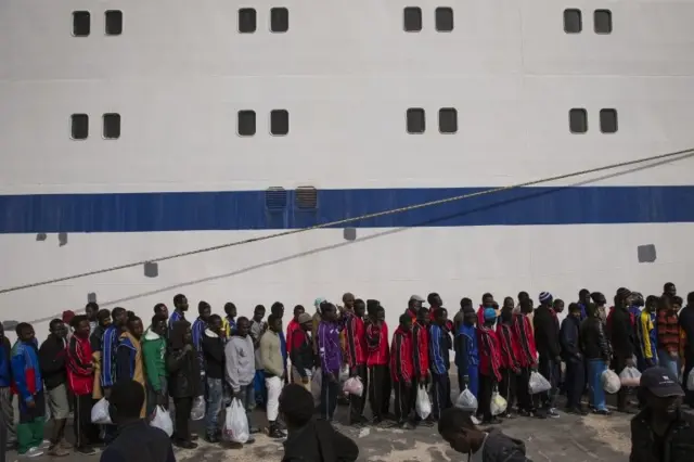 Migrant men wait in line to board a ship bound for Sicily on 23 April 2015 in Lampedusa, Italy.