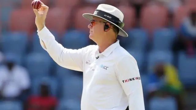 Umpire Bruce Oxenford holds up the new ball