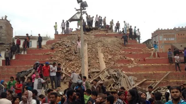 People stand around damage caused by an earthquake at Durbar Square in Kathmandu