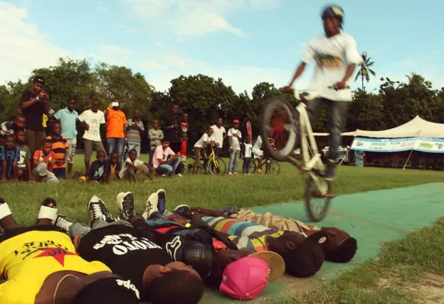 A cyclist leaps over five people
