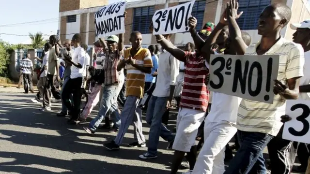 Protesters carry placards as they chant anti-government slogans before clashing with riot policemen in Burundi"s capital Bujumbura