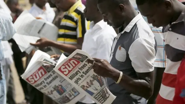 People reading newspapers featuring a front page article about a group of women being rescued by the Nigerian army, in Abuja, Nigeria 29 April 2015