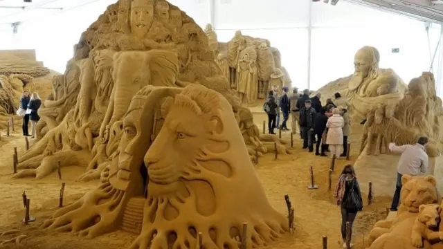 Journalists walk through sculptures made of sand during a tour for the press at the "1. Berliner Sandwelt", festival and exhibition of sand sculptures, in Elstal, Germany, 29 April 2015. Twenty international artists used around 1,100 tons of sand to craft their sand sculptures presenting their artistic visions of Africa.