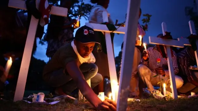 Kenya Red Cross team members light candles among crosses on the ground as they attend the second day of candlelight vigil held for the 148 people killed in an attack on Garissa University College