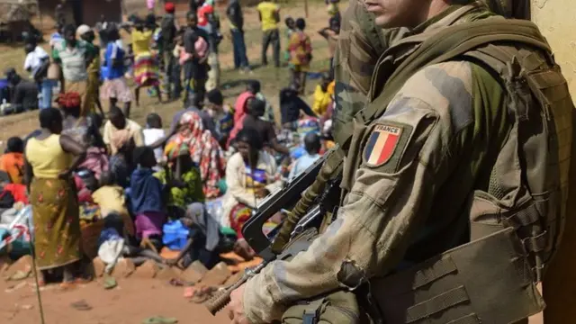 A file picture taken on 19 January 2014 shows a French soldier taking part in "Operation Sangaris" standing guard as Muslim people wait to seek refuge at the Boali church, in Boali, north of Bangui