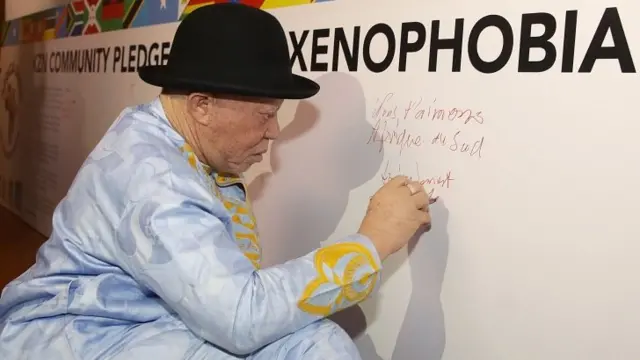 Malian singer Salif Keita writes a message on anti-xenophobia banner during the annual Awesome Africa International Arts Festival held at the Natal Playhouse in Durban