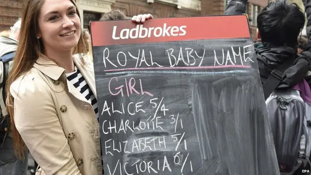 A betting shop employee holds a betting board