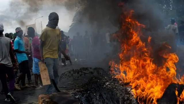 Protesters stand at a burning barricade in the Musaga neighbourhood of Bujumbura, Burundi, on 5 May 2015