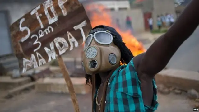 Burundian protester wearing a gas mask and holding a sign that reads "Stop the third mandate" in the Mugasa neighbourhood of Bujumbura on 6 May 2015