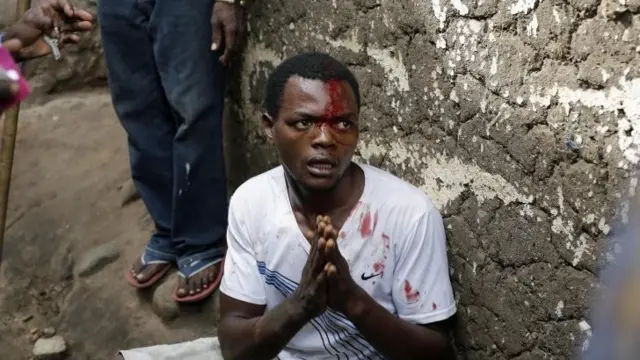 A suspected member of the ruling party's Imbonerakure youth militia pleads for his life as he is surrounded at his house by demonstrators protesting President Pierre Nkurunziza's decision to seek a third term in office in Bujumbura, Burundi, Thursday 7 May 2015