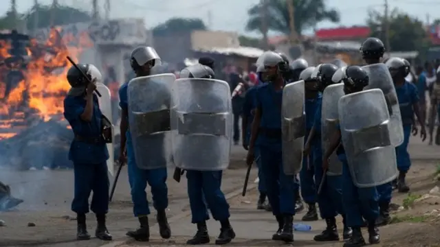 Police march past burning barricades down the main road in the Cibitoke neighbourhood of Bujumbura, on May 7