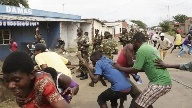 Demonstrators duck and run from soldiers firing into the air to disperse a crowd of demonstrators who had cornered a suspected member of the ruling party's Imbonerakure youth wing in a sewer in the Cibitoke district of Bujumbura, Burundi, Thursday 7 May 2015