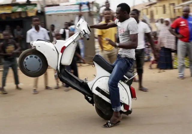 A man pulls a wheelie on a scooter, as residents celebrate the anticipated victory of Presidential candidate Muhammadu Buhari in Kaduna, Nigeria, Tuesday, March 31, 2015