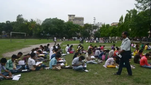 Indian students sit an exam outside