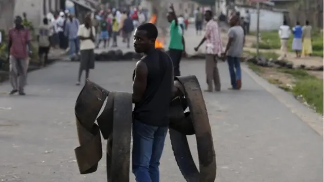 A man carries parts from old tyres to set up a burning barricade during a protest against President Pierre Nkurunziza's decision to run for a third term, in the Buterere neighbourhood of Bujumbura, Burundi on 13 May 2015