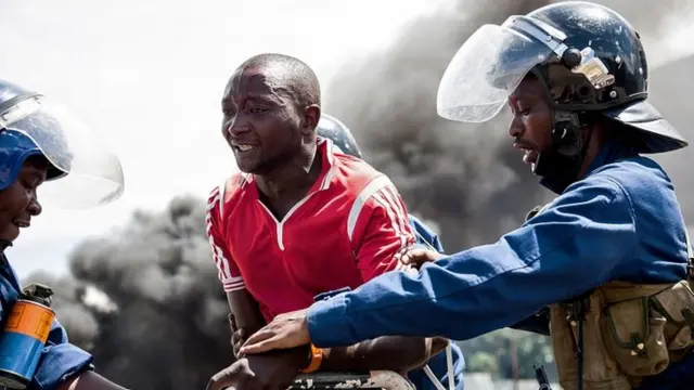 Police officers detain a man during a protest in Bujumbura on 13 May 2015