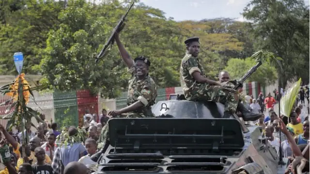 Burundi army soldier riding in an armoured vehicle raises his gun in the air as he joins demonstrators celebrating what they perceive to be an attempted military coup d"etat, in the capital Bujumbura, Burundi Wednesday, 13 May 2015