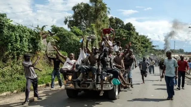 Men on a vehicle celebrate as people take the streets, waving branches, beeping car horns and parading through Bujumbura on 13 May 2015