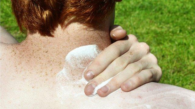 A man protecting the back of his neck with sunscreen