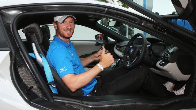 Golfer Chris Wood poses after winning a car for a hole-in-one at the PGA Championship at Wentworth