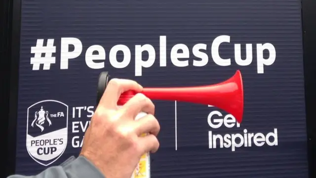 hand holding an air hooter in front of People's Cup signage