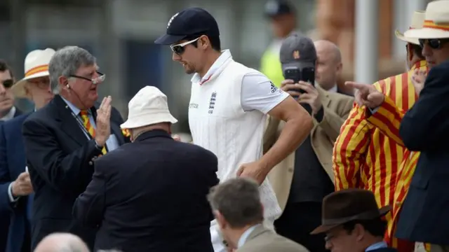 Alastair Cook walks past MCC members