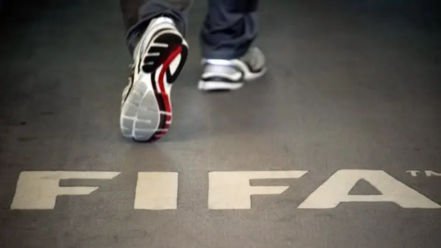 This file photo taken on September 3, 2013 shows a man walking past the logo of the FIFA