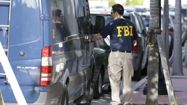 An FBI agent retrieves equipment from a van as he prepares to re-enter the CONCACAF headquarters in Miami. Photo: 27 May 2015