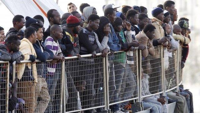 Migrants wait to disembark from a coastguard vessel at Messina harbor, Sicily, 6 May 2015