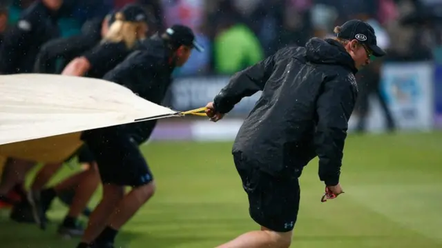 Groundsmen pull on covers