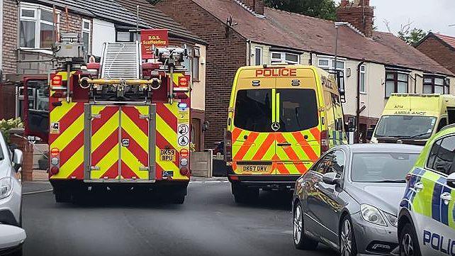 A fire engine, police van and ambulance is within a cordon on a residential street after police discovered explosives in a man's house.