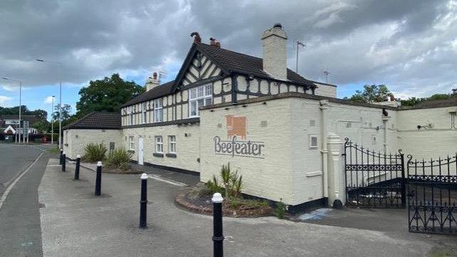 The front of the Glegg Arms, a white-washed building with a timber box frame and the orange Beefeater cow logo on an outer block