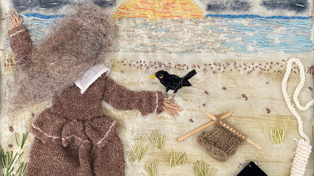 Quilted panel made from fabric depicts a woman with grey hair in a long grey dress or gown, with a crow-like bird on her right hand. She appears to be looking out to sea where the sun is going down. Knitting needles and knitting can be seen, along with the top part of a hangman's rope.