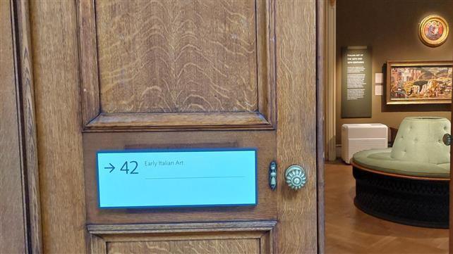 The door of the Early Italian Art Gallery at the Ashmolean Museum. It is open and some of the paintings inside could be seen. A green sofa could be seen in the middle