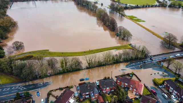 An aerial view of houses and fields partially submerged in brown flood-water