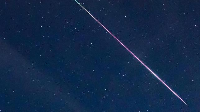 A shooting star flying over the night sky.