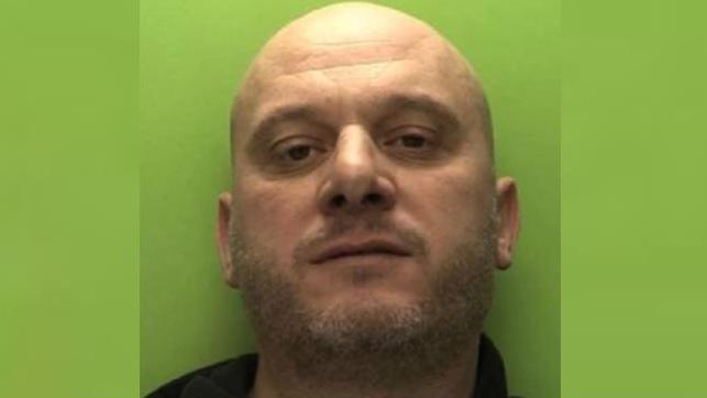 Police custody photo of Arsen Feci. He is bald and has a stubble beard.