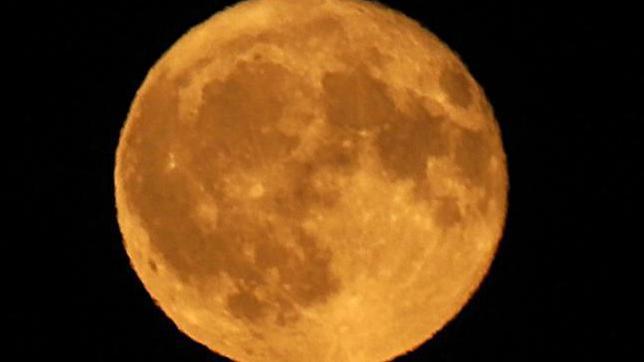 A black background with a huge full moon in the centre, tinged orange